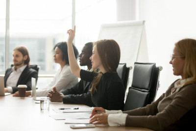 This is an image of a young woman putting her hand up to ask a question